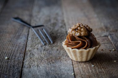 Bir mum bir ahşap mutfak masasında Cupcake tatma. Koyu arka plan.
