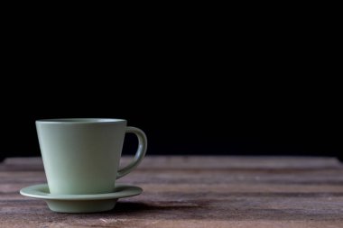 Kahve bardağı ahşap bir masa üzerinde. Siyah arka plan.