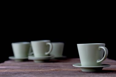 Kahve bardağı ahşap bir masa üzerinde. Siyah arka plan.