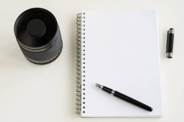 Defter ve kalem ofiste beyaz bir tabloda.