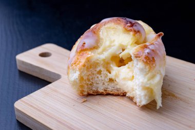 Tatlı krema ile küçük bir tahta üzerinde rulo. Lezzetli tatlı mutfak masasının üzerinde. Koyu arka plan.