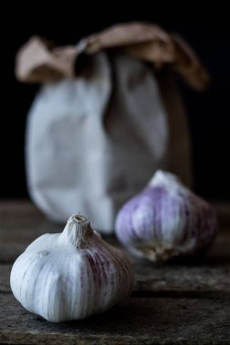 Soğan ve sarımsak bir kağıt torba. Koyu ahşap masa.