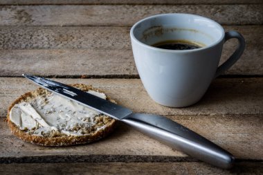 Ahşap bir masa ekmek ve kahve kupa. Yemek kahvaltı hazırladım. Koyu arka plan.