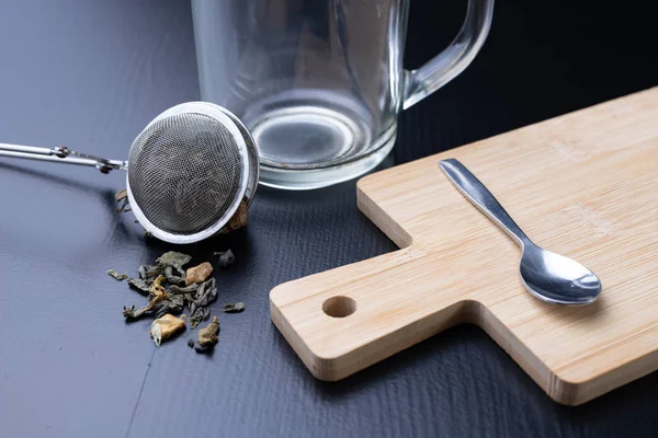 Brewing tea on a black table. Mug with a warm drink. Dark background.