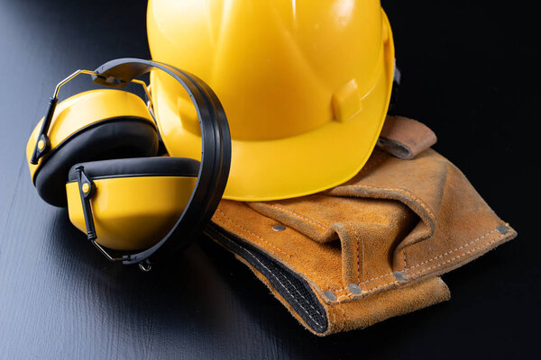 Helmet and accessories for construction workers. Accessories needed for work on the construction site. Dark background.