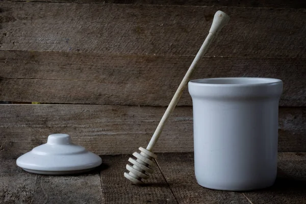 Honey spoon and jug on a wooden table.