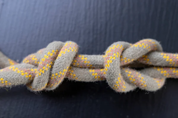 A knot tied on a sailing line. A rope for sailors and travelers on the table. Dark background.