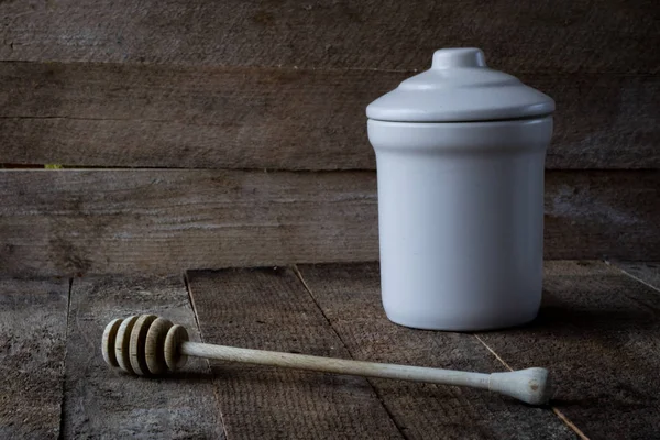 Honey spoon and jug on a wooden table.