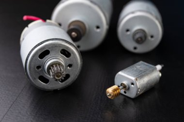 Ahşap bir karanlık tabloda küçük elektrikli motor. Küçük ev aletleri için elektrikli sürücü. Koyu arka plan.