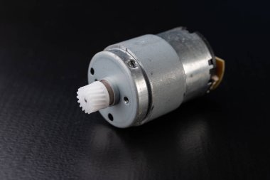 Ahşap bir karanlık tabloda küçük elektrikli motor. Küçük ev aletleri için elektrikli sürücü. Koyu arka plan.