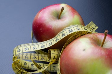 Lezzetli, Olgun elma bir ölçüm bandı sarılmış. Meyve karanlık bir tablo. Siyah arka plan.