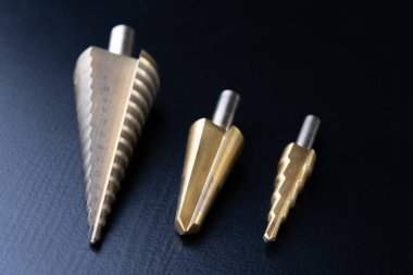 Konik matkaplar bir atölye tablo. Mekanik delikler yapmak için aksesuarlar. Koyu arka plan.