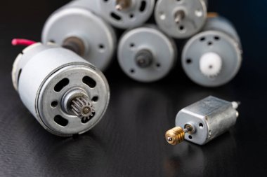 Ahşap bir karanlık tabloda küçük elektrikli motor. Küçük ev aletleri için elektrikli sürücü. Koyu arka plan.