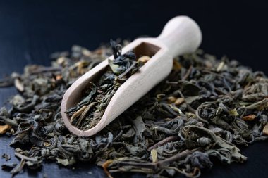 Çay yaprakları ve ahşap bıyık. En iyi çeşitleri çay karışımı. Koyu arka plan.