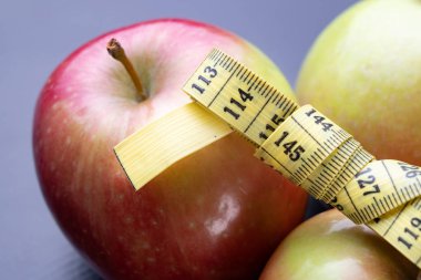 Lezzetli, Olgun elma bir ölçüm bandı sarılmış. Meyve karanlık bir tablo. Siyah arka plan.