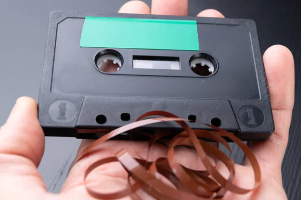 Audio cassette with space for text entry on the palm of your hand. Cassette without description. Dark background.