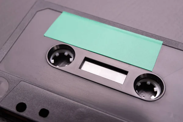 Audio cassette with space for text entry. Cassette without description. Dark background.