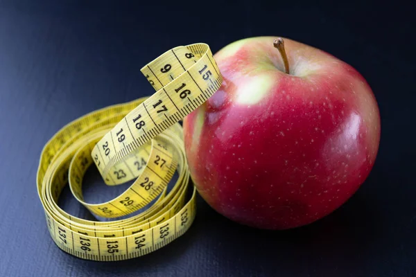 おいしい 完熟りんごは 測定テープに包まれて ダークウッドのテーブルにフルーツ 黒の背景 — ストック写真
