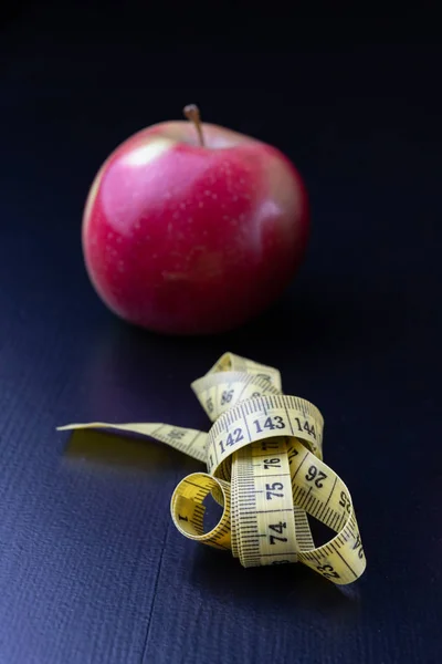 おいしい 完熟りんごは 測定テープに包まれて ダークウッドのテーブルにフルーツ 黒の背景 — ストック写真