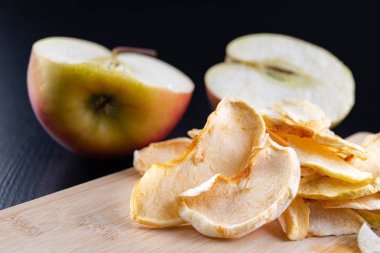 Lezzetli mutfak masasının üzerinde kurutulmuş elma parçaları. Lezzetli tatlılar tatlı eklemeler. Koyu arka plan.