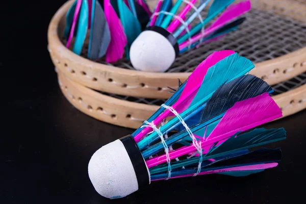 Colorful feathers in the badminton shuttlecock. Team play set. Dark background.