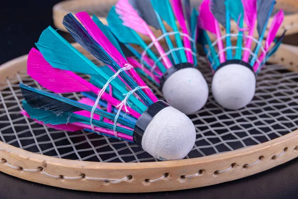 Colorful feathers in the badminton shuttlecock. Team play set. Dark background.