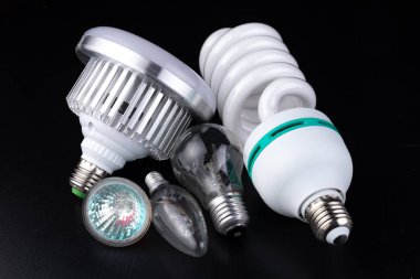 Farklı Işık Ampüller ve ahşap bir masa floresan ışıkları. Aydınlatma yeni tip. Koyu arka plan.