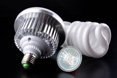 Farklı Işık Ampüller ve ahşap bir masa floresan ışıkları. Aydınlatma yeni tip. Koyu arka plan.