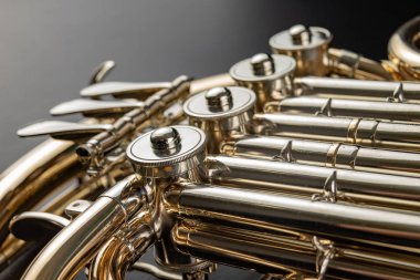 Ahşap bir masa üzerinde Fransız kornosu. Güzel cilalı müzik aleti. Koyu arka plan.