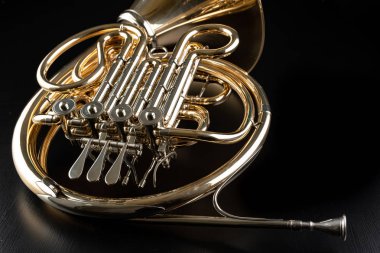 Ahşap bir masa üzerinde Fransız kornosu. Güzel cilalı müzik aleti. Koyu arka plan.