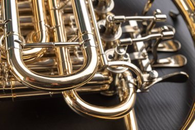 Ahşap bir masa üzerinde Fransız kornosu. Güzel cilalı müzik aleti. Koyu arka plan.