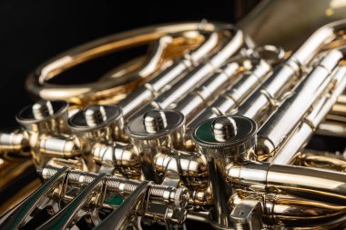 Ahşap bir masa üzerinde Fransız kornosu. Güzel cilalı müzik aleti. Koyu arka plan.