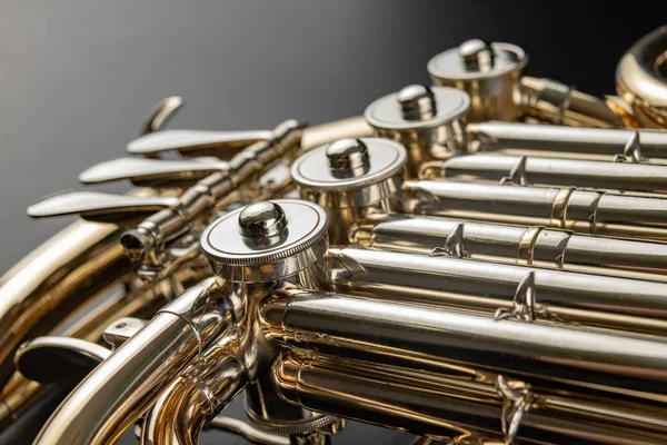 Ahşap bir masa üzerinde Fransız kornosu. Güzel cilalı müzik aleti. Koyu arka plan.