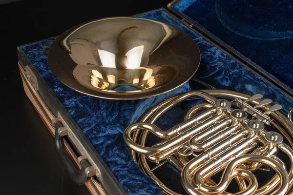 Fransız kornosu ahşap bir masa üzerinde eski bir durumda. Güzel cilalı müzik aleti. Koyu arka plan.