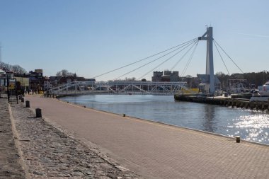Ustka, pomorskie / Poland - February, 22, 2019: Pedestrian bridge through the port channel in Ustka. Harbor buildings in Poland. Season winter. clipart