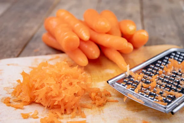 Petites carottes râpées sur une table de cuisine. Légumes préparés pour — Photo