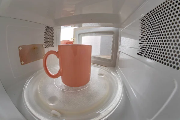 Кружка, стоящая на микроволновке. Устройство для нагрева посуды w — стоковое фото