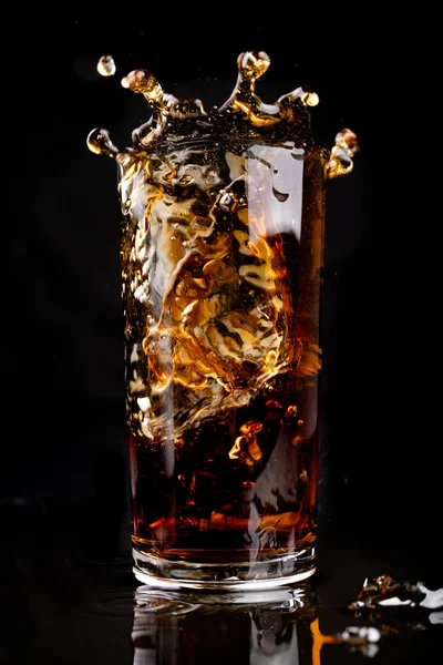Бросать лёд в стакан с холодным напитком. Выплеск напитка — стоковое фото