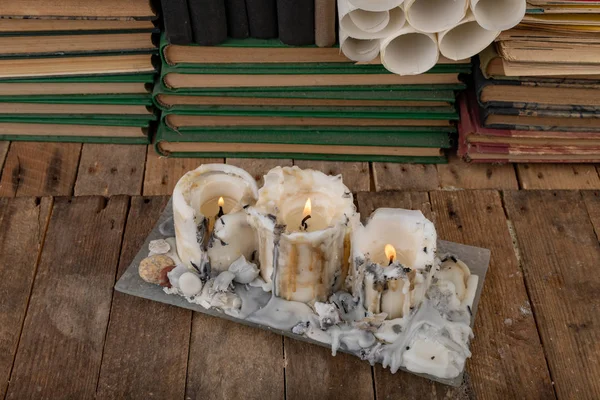 Burned candle on the background of old books. Desk of an old wri — Stock Photo, Image