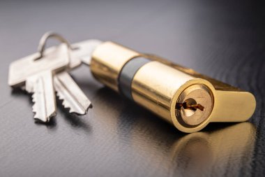 Karanlık bir arka planda yeni bir kapı kilidi. Bir patent ve anahtarları SECUR