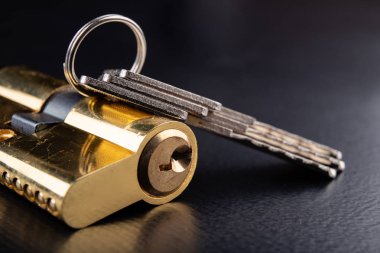 Karanlık bir arka planda yeni bir kapı kilidi. Bir patent ve anahtarları SECUR