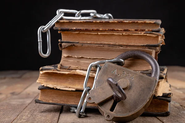 Old books bound by a new shiny chain with an old padlock. Forbid