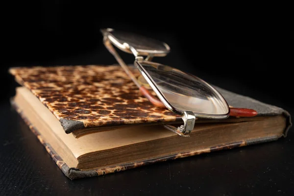 一张深色木桌上的旧书和眼镜。被遗忘的发布 — 图库照片