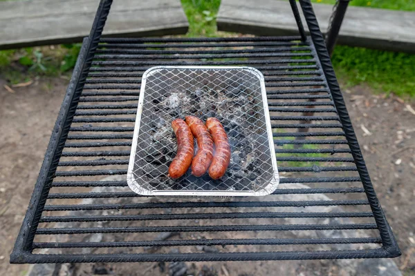 Salchichas asadas en la parrilla. Preparación de una comida en un camping . — Foto de Stock