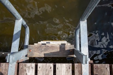 Ahşap iskelede metal bir merdiven. Lak'ta suya iniş