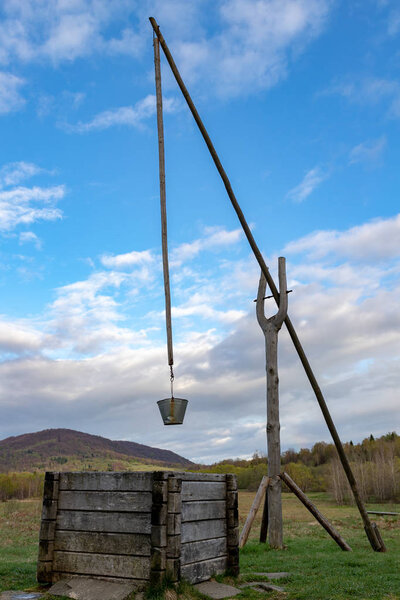 An old well in the mountains with a crane. Place of water collec