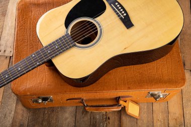 Klasik gitar ve bavul koyu ahşap bir masa üzerinde. Telli m