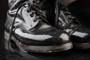 Eski siyah ordu botları yağmurdan ıslanıyor. Di'ye dayanıklı ayakkabı