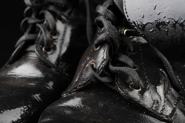 Old black army boots wet from the rain. Footwear resistant to di
