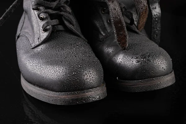 Black military boots and rain drops. Well-preserved old boots fo